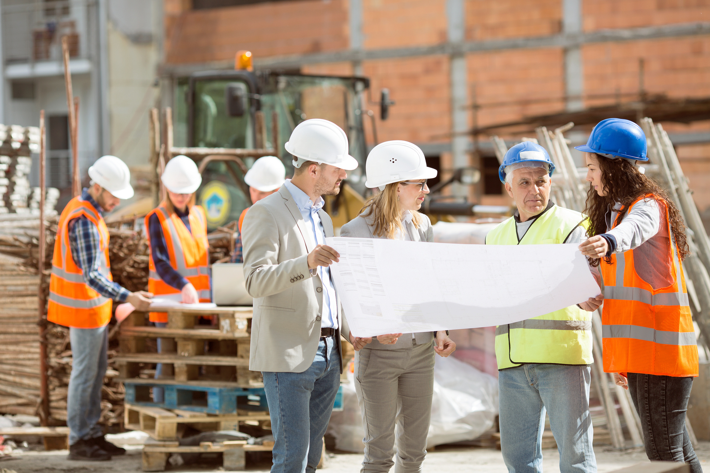 Group Construction workers looking at blueprints on construction site